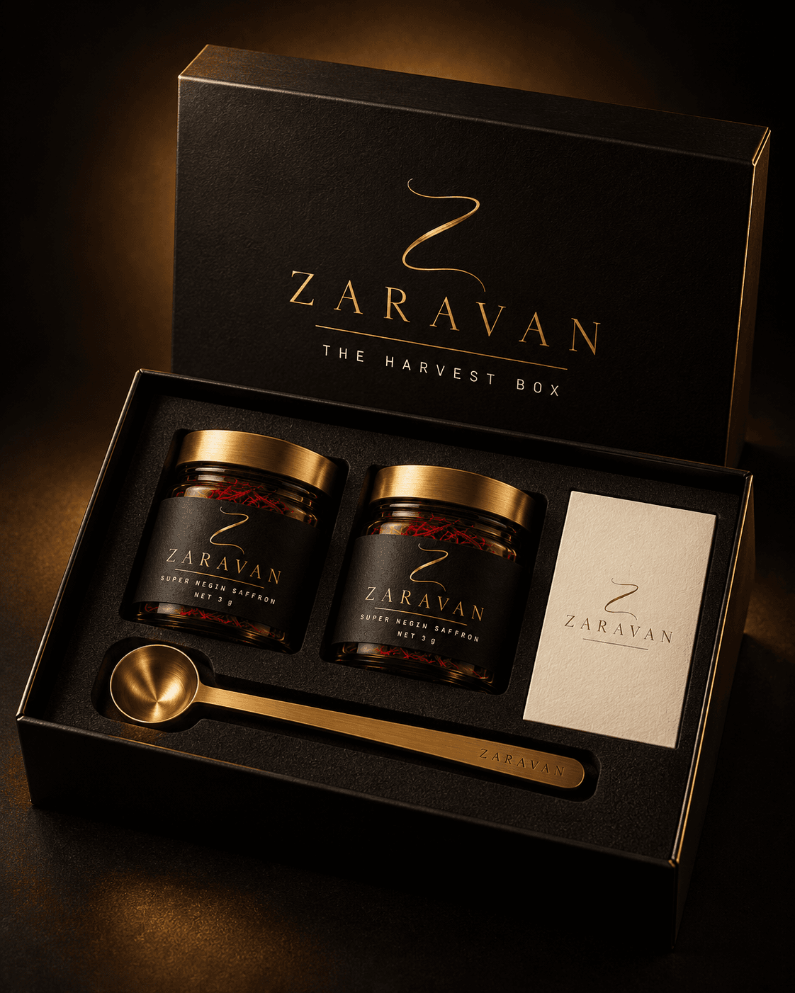 Open black gift box holding two saffron jars, a brass measuring spoon and a card.