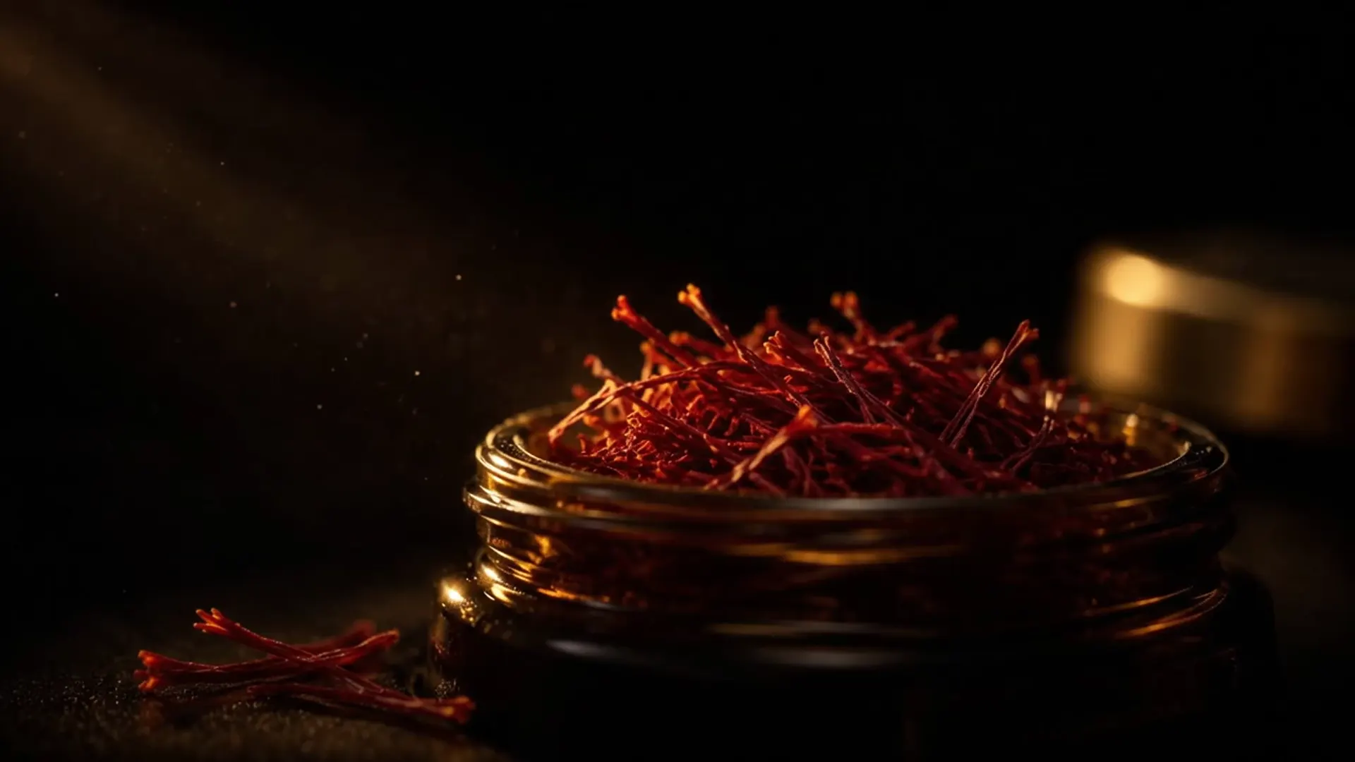 Saffron threads falling into an open jar of Zaravan Super Negin.
